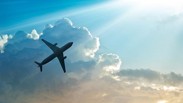 airliner flying in front of clouds and sunbeams